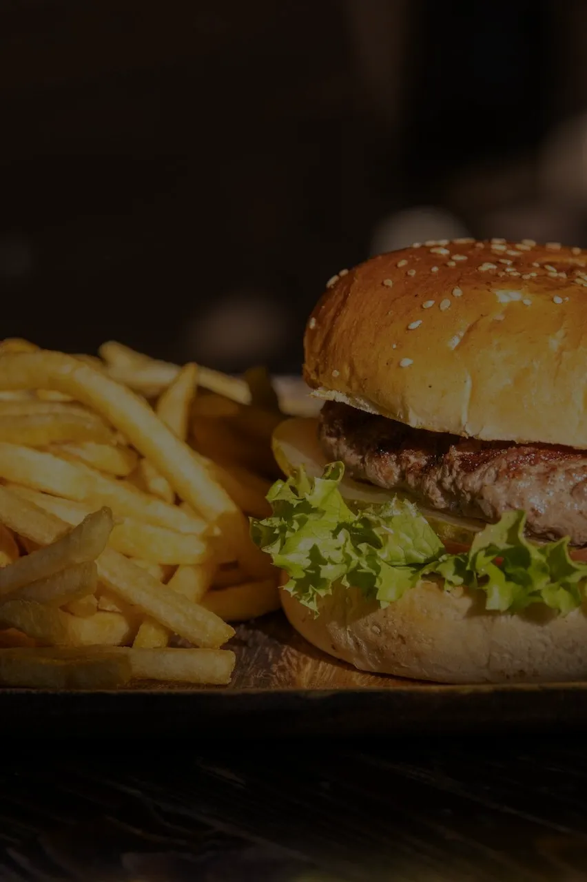 Hamburguesa con papas fritas servidas en un plato de madera